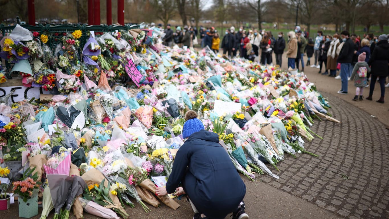 Eine Frau legt Blumen an der Gedenkstätte für die entführte und getötete Sarah Everard in London nieder.