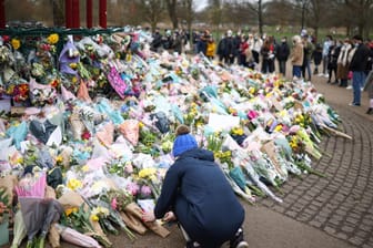 Eine Frau legt Blumen an der Gedenkstätte für die entführte und getötete Sarah Everard in London nieder.