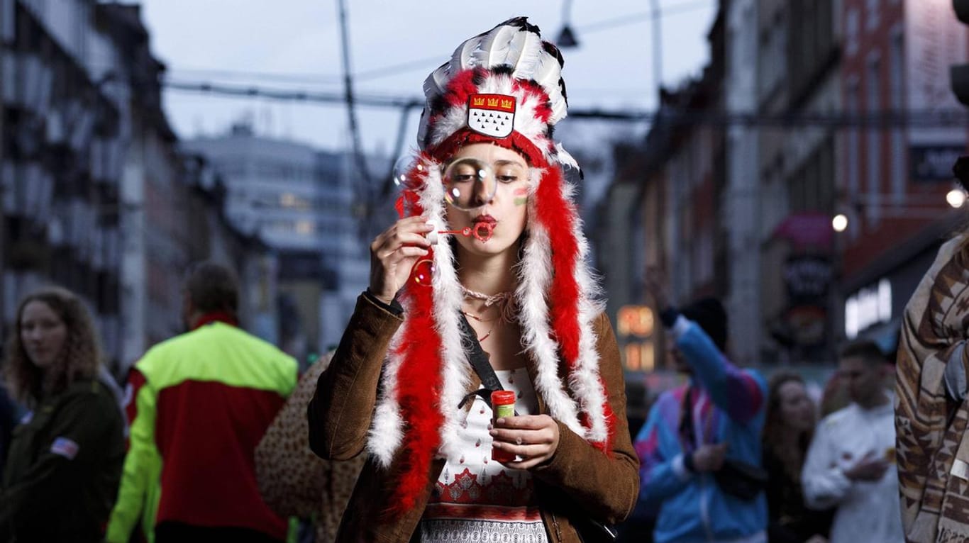 Eine Karnevalistin steht als Indianerin verkleidet auf der Zülpicher Straße (Archivbild): Geht es nach einem Antrag der Jusos, soll es solche Kostüme künftig nicht mehr geben.