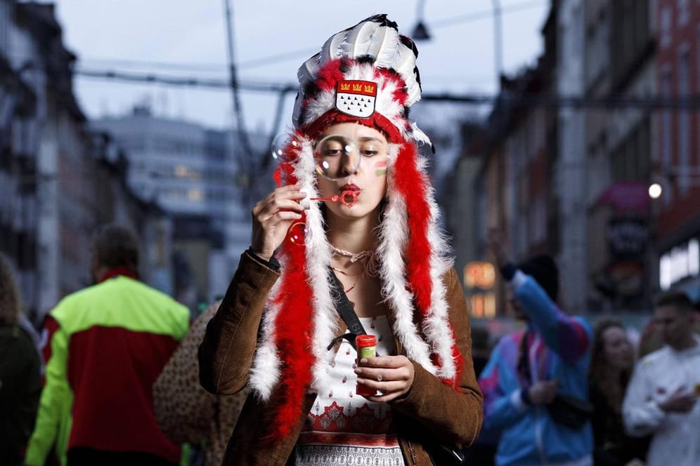 Eine Karnevalistin steht als Indianerin verkleidet auf der Zülpicher Straße (Archivbild): Geht es nach einem Antrag der Jusos, soll es solche Kostüme künftig nicht mehr geben.