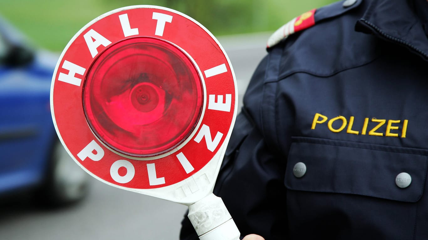 Ein Polizist hält eine "Stopp"-Kelle in der Hand (Symbolbild): Bei einer vermeintlichen Kontrolle erbeutete ein Polizist Bargeld.