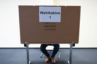 Ein Mann sitzt im Wahlraum des Briefwahllokals Frankfurt Innenstadt hinter einer Wahlkabine.