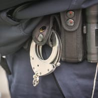 Handschellen hängen am Gürtel eines Polizeibeamten (Symbolbild): In Wuppertal ist ein mutmaßlicher Drogendealer festgenommen worden.