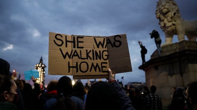 Eine Person hält inmitten einer Menschenmenge in der Nähe des Parlaments in London ein Plakat mit der Aufschrift "She was walking home" ("Sie ging nach Hause") in die Höhe. Eine Person hält inmitten einer Menschenmenge in der Nähe des Parlaments in London ein Plakat mit der Aufschrift "She was walking home" ("Sie ging nach Hause") in die Höhe.