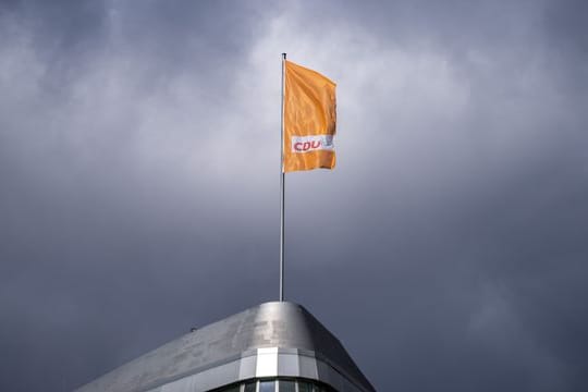Die CDU-Fahne weht auf dem Konrad-Adenauer-Haus in Berlin - vor dunklen Wolken.