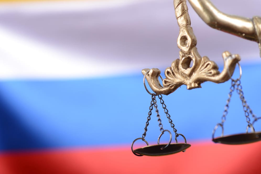Justitia, das Symbol der Gerechtigkeit, vor der russischen Flagge: Nach einer brutalen Hinrichtung muss sich die russische Söldner-Gruppe "Wagner" vor Gericht verantworten.