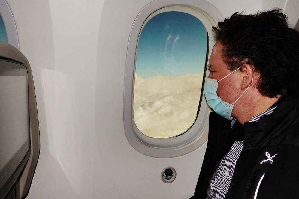 Passagier mit Mund-Nasen-Schutz im Flugzeug: Die Bundesregierung fordert jetzt auf, auf Reisen zu Ostern zu verzichten.