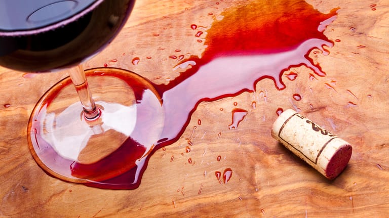 Rotweinfleck: Wer Rotwein auf einem Holztisch verschüttet, sollte ihn direkt entfernen.