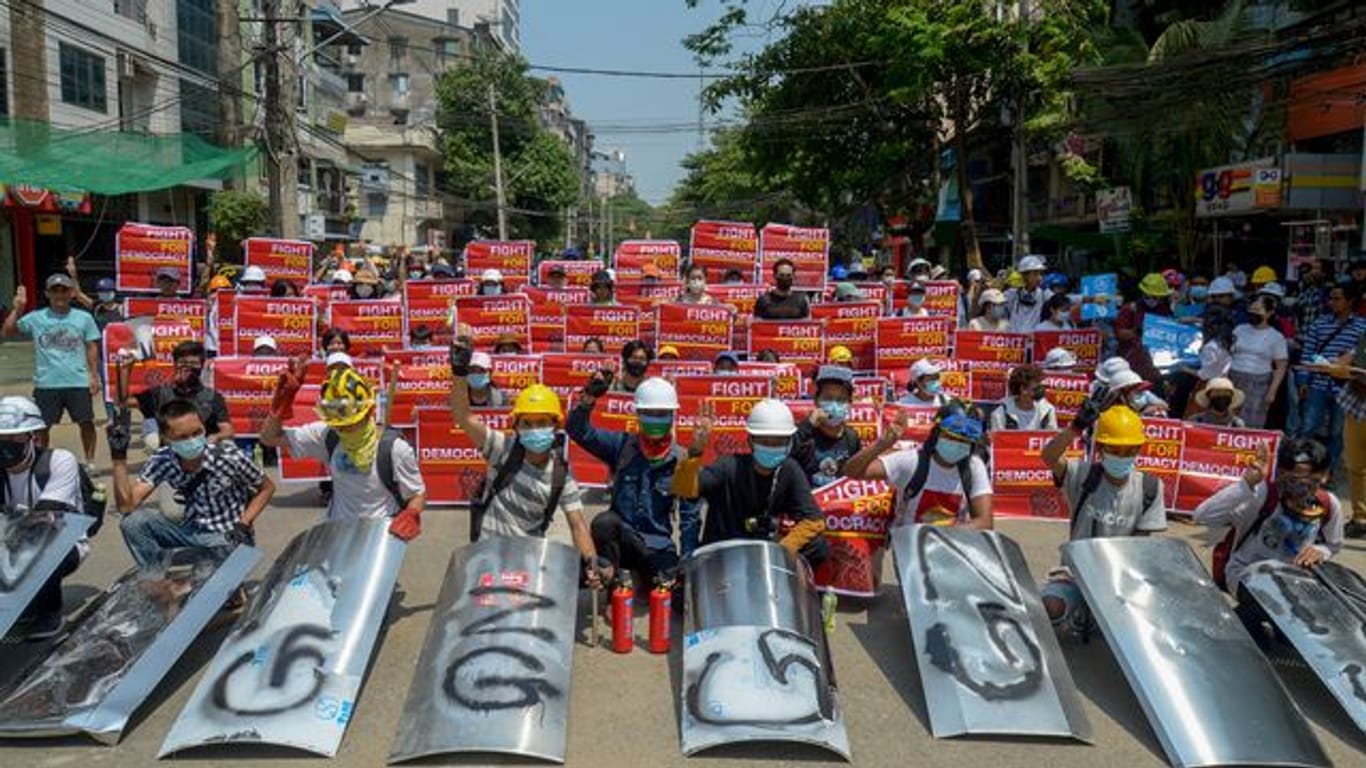 Demonstranten versammeln sich in Yangon und zeigen Plakate.