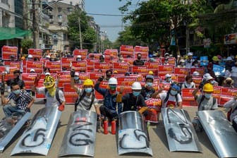Demonstranten versammeln sich in Yangon und zeigen Plakate.