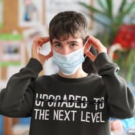 Ein Junge mit Mund-Nasen-Schutz sitzt im Unterricht (Symbolbild): Die Nachfrage von Kölner Schulen an Schnelltests ist groß.