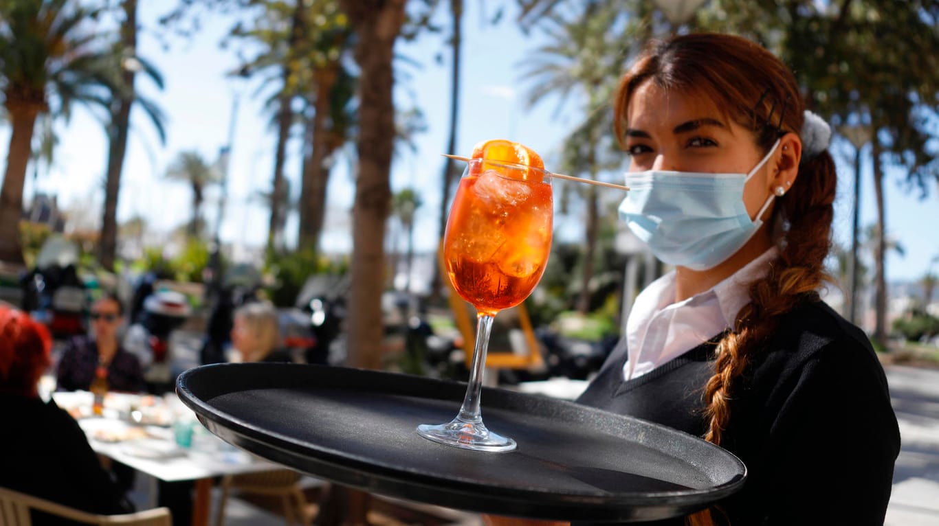 Eine Kellnerin serviert in Palma de Mallorca einen Drink: Ist es angesichts der aktuellen Corona-Lage in Ordnung, auf die Insel zu fliegen?