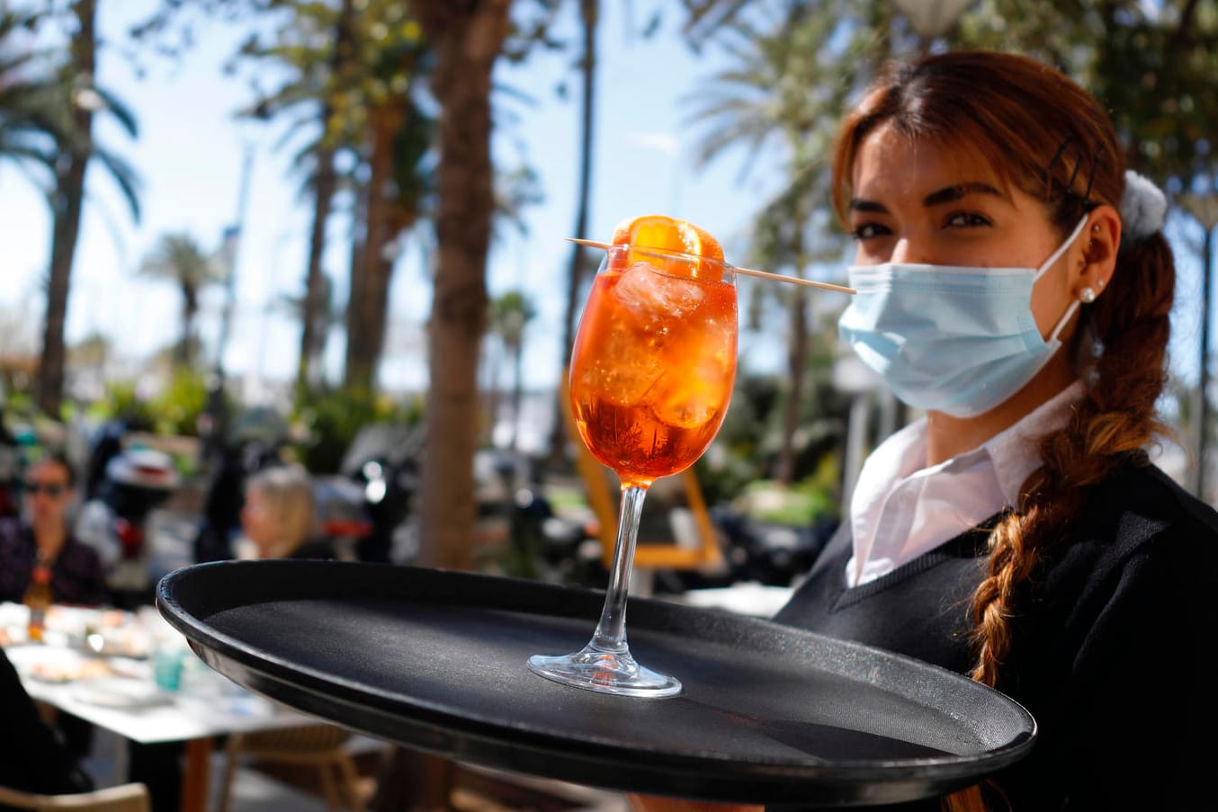 Eine Kellnerin serviert in Palma de Mallorca einen Drink: Ist es angesichts der aktuellen Corona-Lage in Ordnung, auf die Insel zu fliegen?