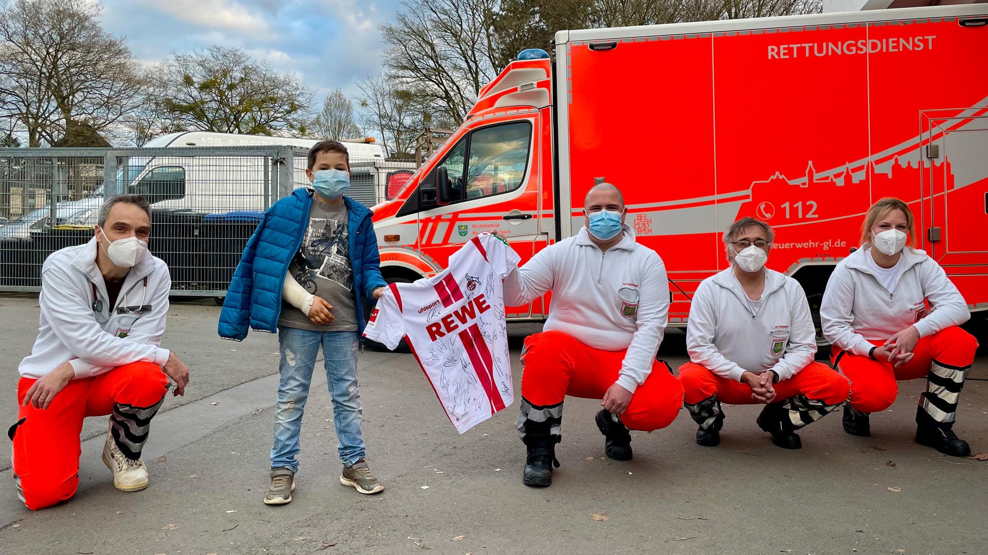 Der neunjährige Noel und seine Helfer vom Rettungsdienst mit dem FC-Trikot: Genesungswünsche vom ganzen Team.