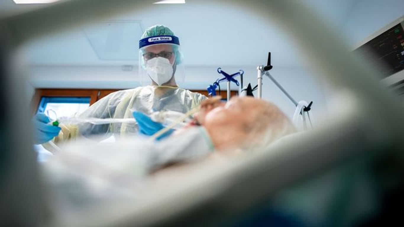 Ein Intensivpfleger arbeitet in Schutzausrüstung auf der Intensivstation des Krankenhauses Bethel in Berlin an einem Corona-Patienten.