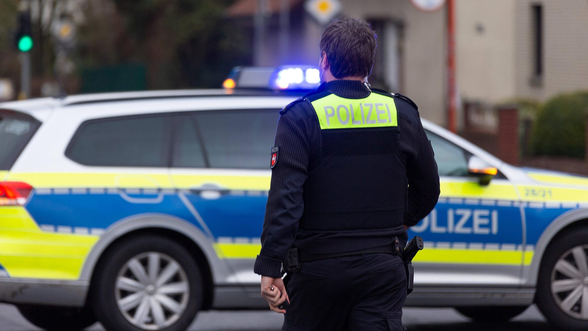 Ein Polizeibeamter mit Schriftzug Polizei auf dem Rücken (Symbolbild): Die Polizei kann nicht ausschließen, dass es einen Zusammenhang zwischen den Einbrüchen gibt.