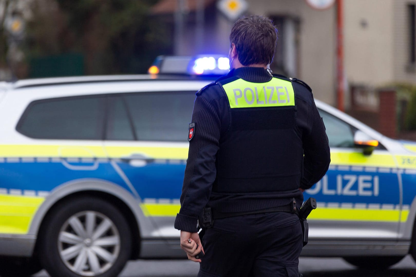 Ein Polizeibeamter mit Schriftzug Polizei auf dem Rücken (Symbolbild): Die Polizei kann nicht ausschließen, dass es einen Zusammenhang zwischen den Einbrüchen gibt.