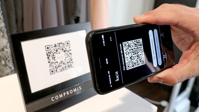 Ein Mann scannt den QR-Code eines Geschäfts mit seiner Luca-App: Durch die App erhält das zuständige Gesundheitsamt die Namen und Telefonnummern von möglichen Kontaktpersonen digital zugespielt.