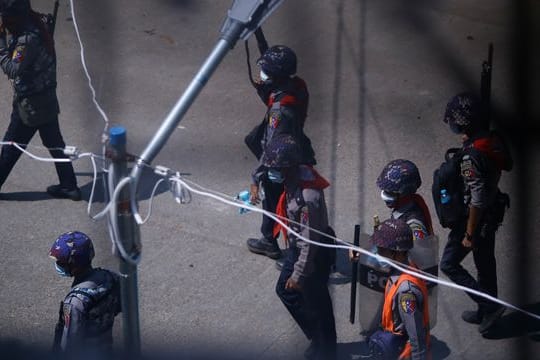 Polizisten patrouillieren schwer bewaffnet auf einer Straße.