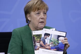 Bundekanzlerin Merkel mit einer Broschüre: Erst ab Ostern soll bei den Hausärzten geimpft werden.