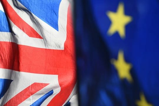Eine Flagge der Europäischen Union und eine Flagge von Großbritannien wehen vor dem Parlament in Westminster.