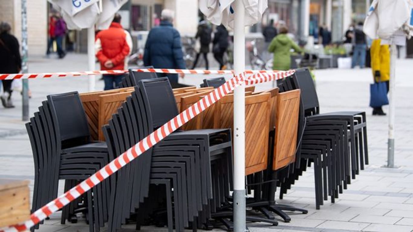 Die Tische und Stühle eines Cafes sind mit Flatterband abgesperrt.