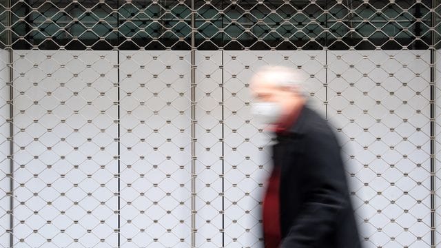 Ein Mann geht in einer Innenstadt an einem geschlossenen Geschäft vorbei. Ein Mann geht in einer Innenstadt an einem geschlossenen Geschäft vorbei.