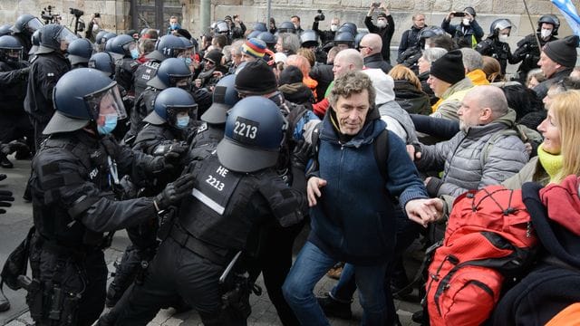 Einsatzkräfte der Polizei halten bei einer Kundgebung Teilnehmer zurück.
