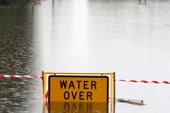 Ein Schild mit Warnhinweis auf einer überfluteten Straße bei Windsor.