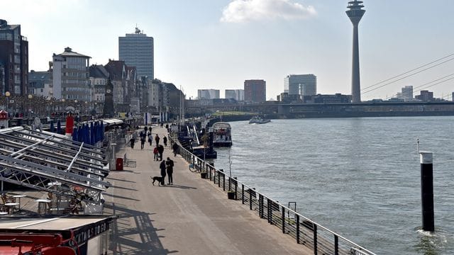 Menschen gehen am Rheinufer entlang (Archivbild): Die Düsseldorfer Feuerwehr hat einen vermissten Hund gerettet.