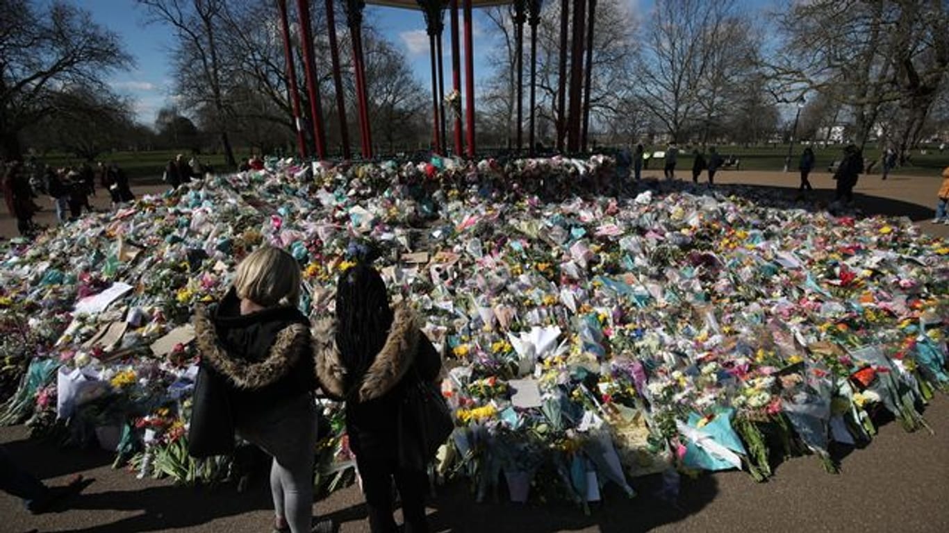 Zwei Frauen schauen sich die Blumen an, die für die getötete Sarah Everard im Clapham Common Park in London niedergelegt wurden.