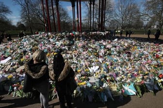 Zwei Frauen schauen sich die Blumen an, die für die getötete Sarah Everard im Clapham Common Park in London niedergelegt wurden.