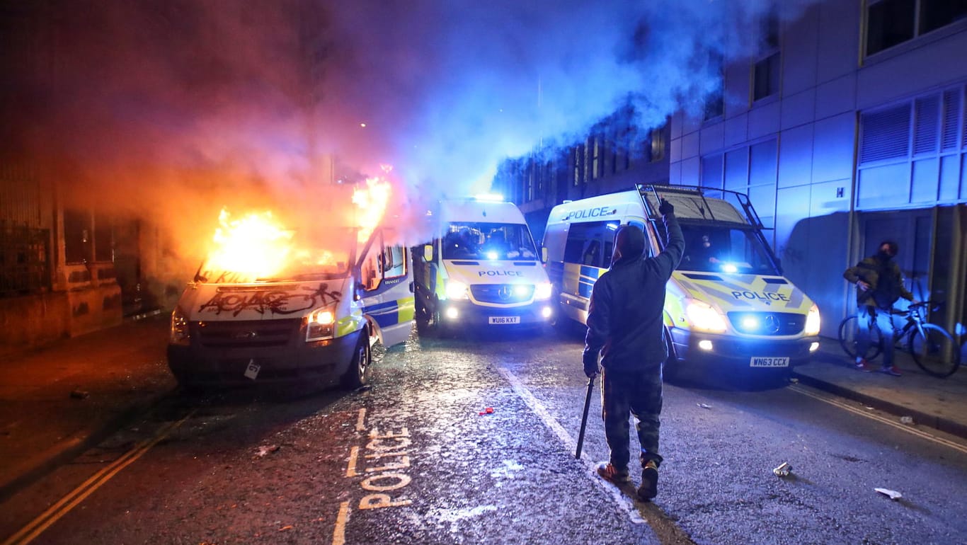 Randalierer in Bristol: Im Hintergrund brennt ein Polizeiauto.
