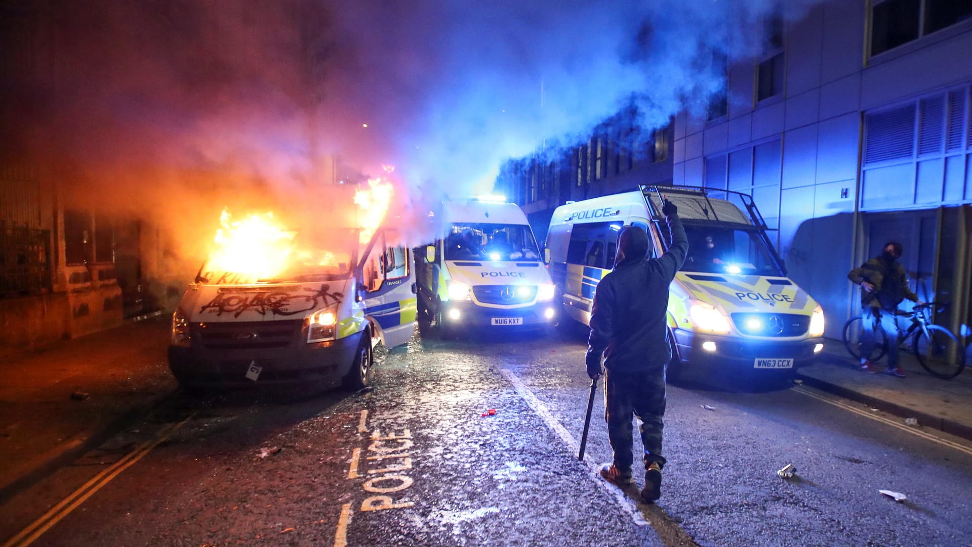 Randalierer in Bristol: Im Hintergrund brennt ein Polizeiauto. Randalierer in Bristol: Im Hintergrund brennt ein Polizeiauto.
