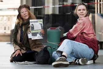 Monika Keller (Rike Eckermann, l) verkauft am Dom Obdachlosenzeitungen.