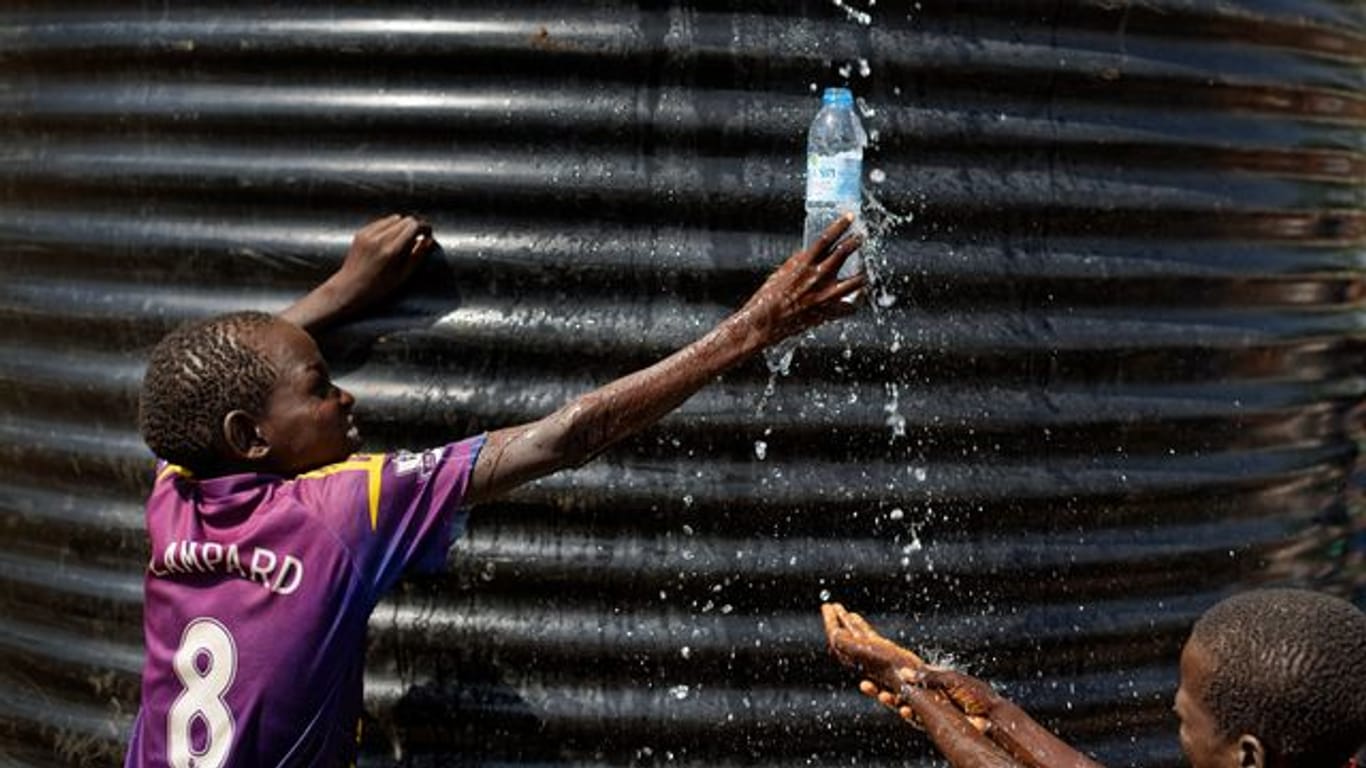 Ein Flüchtlingsjunge aus dem Südsudan fängt in einer Empfangsstelle für Flüchtlinge in Imvepi (Uganda) mit einer Flasche Wasser auf.