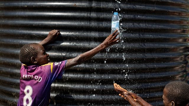 Ein Flüchtlingsjunge aus dem Südsudan fängt in einer Empfangsstelle für Flüchtlinge in Imvepi (Uganda) mit einer Flasche Wasser auf.