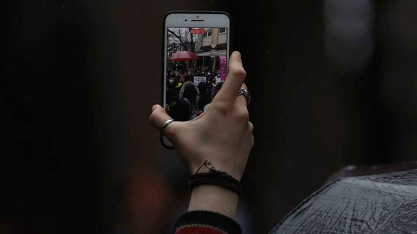 Eine Frau filmt Demonstranten während einer Kundgebung in Ankara mit ihrem Handy.