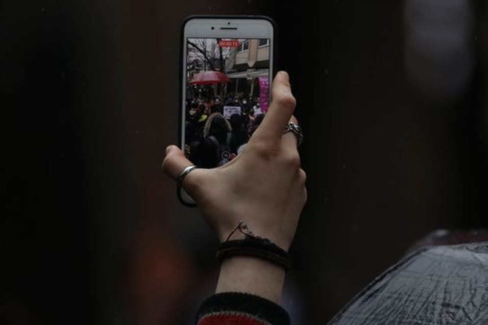 Eine Frau filmt Demonstranten während einer Kundgebung in Ankara mit ihrem Handy.