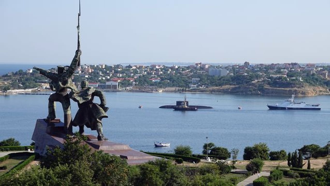 Hinter dem sowjetischen Denkmal "Soldat und Seemann" liegen ein U-Boot und Kriegsschiffe der russischen Schwarzmeerflotte vor Anker in der Hafenstadt Sewastopol.