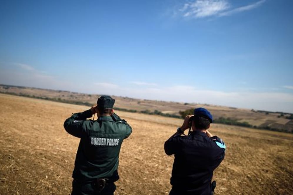 Zwei Beamte der europäischen Grenzschutzagentur Frontex aus Bulgarien (l) und den Niederlanden beobachten mit Ferngläsern die bulgarisch-türkische Grenze.