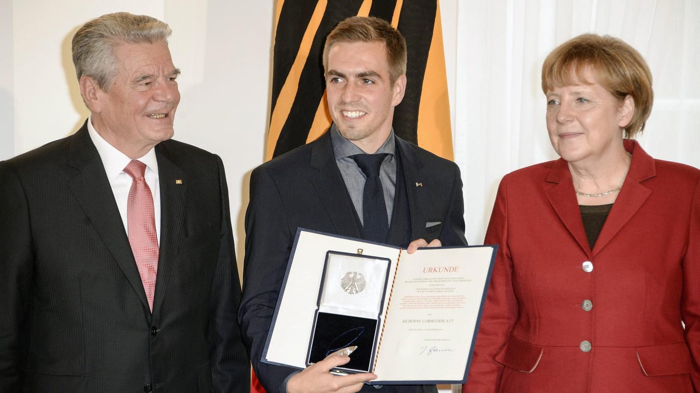 Im Jahr 2014 bei der Verleihung des Silbernen Lorbeerblattes für die Fußball-Nationalmannschaft: Lahm mit dem ehemaligen Bundespräsidenten Gauck und Kanzlerin Merkel.