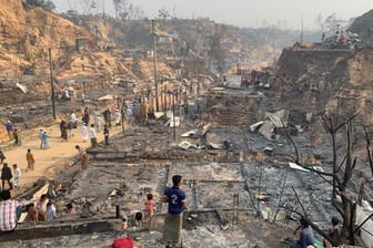 Rohingya-Geflüchtete betrachten nach dem Brand die Überreste des Flüchtlingslager.
