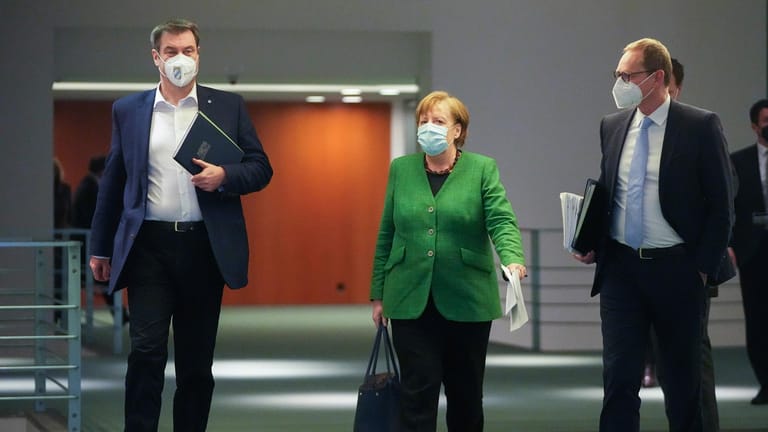 Markus Söder, Angela Merkel und Michael Müller auf dem Weg zur Pressekonferenz nach dem Corona-Gipfel: Nach mehr als zwölf Stunden Verhandlung steht der Beschluss.