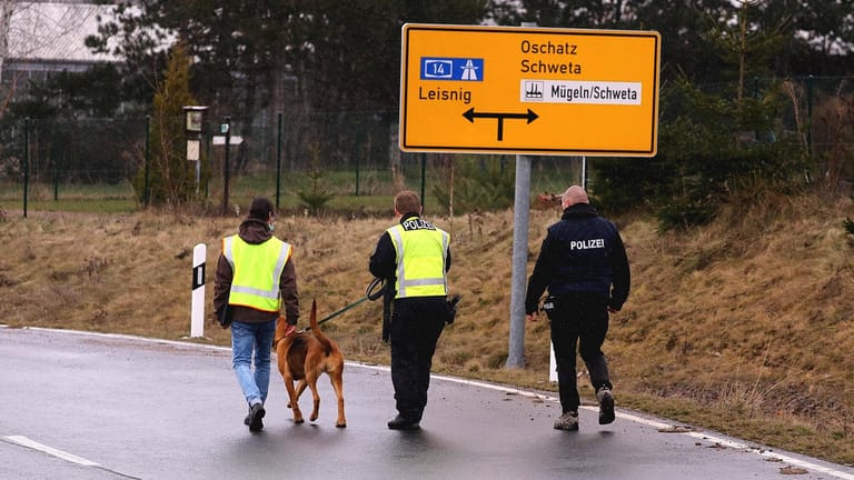 Polizisten laufen mit Spürhunden den Fundort ab: Noch sind die Todesumstände unklar.