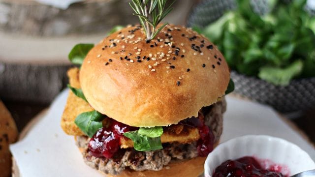 Zwischen die selbst gebackenen Brötchen-Hälften werden Hackfleisch-Patties, panierte Camembert-Streifen, Preiselbeeren und Feldsalat geschichtet.