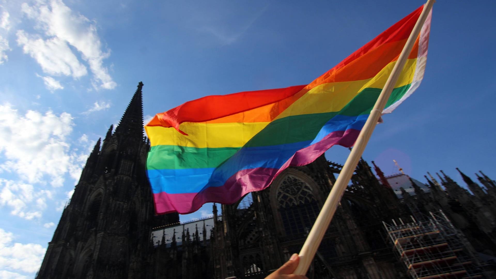 Eine Regenbogenflagge wird vor dem Kölner Dom in die Luft gehalten (Archivbild): Das Bistum Köln stützt das Segnungsverbot für homosexuelle Paare.