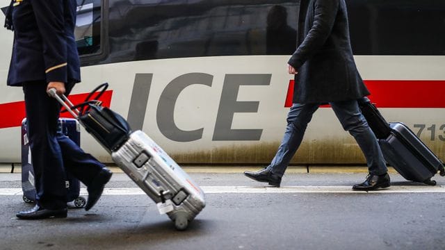 Fahrgäste gehen mit ihrem Gepäck an einem ICE-Zug vorbei. Fahrgäste gehen mit ihrem Gepäck an einem ICE-Zug vorbei.