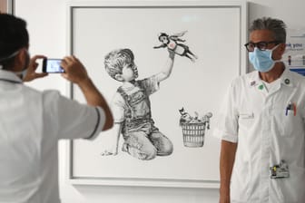 Ein Krankenhausmitarbeiter lässt sich vor dem Werk "Game Changer" von Banksy fotografieren: Der Schätzwert hatte bei 2,5 bis 3,5 Millionen Pfund gelegen.