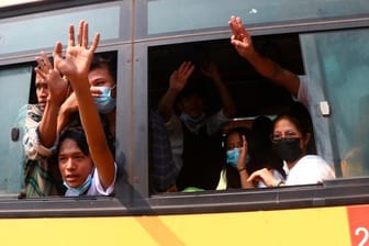 Festgenommene Demonstranten winken Menschen, während sie in einem Bus sitzen, der aus dem Insein-Gefängnis kommt und sie zu einem ungenannten Ort transportieren wird.